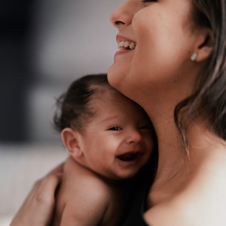 Glückliche Mutter hält ihr schlafendes Baby im Arm – nach vertrauensvoller digitaler Begleitung durch ihre Hebamme.